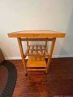 Front view of wood kitchen cart showing top, shelves and casters
