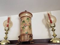 Overall view showing painted urn pedestal flanked by the two brass hurricane candle holders