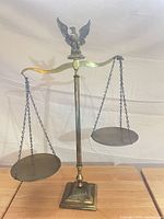 Front view of brass balance scale showing eagle finial, beam, chains and pans