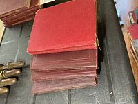 Stack of five small red/maroon military manuals showing cloth covers and size