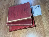 Stack of three red Quarterly Militia List volumes showing covers and wear