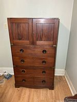 front view of rosewood campaign chest showing paneled top section and three drawers