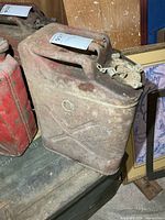 Front of red metal US jerry can showing X pattern and embossing