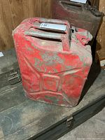 front view of red metal fuel can showing wear and embossing