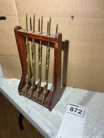 Front view of wooden stand holding four brass letter openers