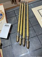 Four brass rods laid side by side showing full length