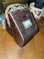 Oblique view of closed transit case showing overall form and leather strap