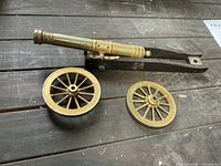 Metal cannon barrel on wood carriage with two loose wheels