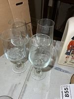 Four matching etched D-Day anniversary goblets on table