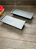 Top view of both black rectangular resin shelves on wood floor