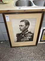 Full view of framed King George VI portrait leaning against cabinet