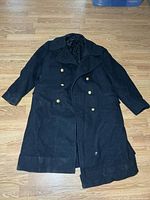 Full view of black wool overcoat laid flat showing length and overall design