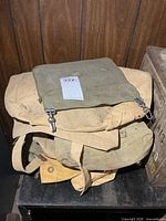 Stack showing olive drab pouch atop two tan rucksacks