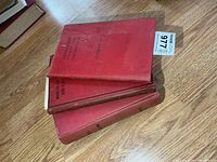 Stack of four red cloth military books on floor