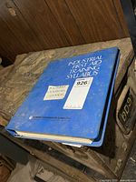 Blue binder marked Industrial First Aid Training Syllabus containing the manual