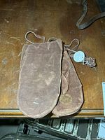 Top view of both brown suede mittens attached together showing overall condition