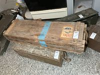 Full view of top and side of wooden ammunition crate showing stenciled text and blue stripe