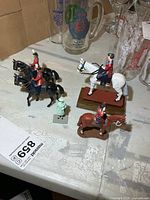 Five Queen Elizabeth II figurines including four on horses and one standing