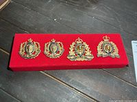 All four RCMP badges on red felt backer