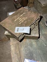 Two stacked olive drab metal first aid boxes on table