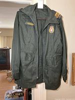 Full view of dark green uniform jacket hanging
