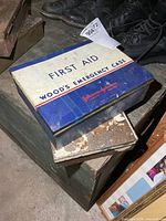 Top view showing Johnson & Johnson Wood's Emergency Case tin and smaller rusty white tin