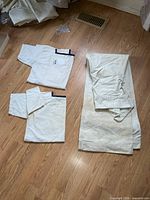Two folded shirts and one pair trousers on floor