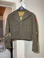 Front view of olive drab RCAC battle dress jacket hanging