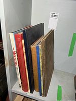 Stack of six large hardcovers standing on shelf