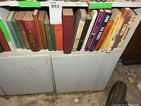 Wide view of shelf showing left and right groups of vintage books with lot sticker
