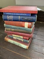 Stack of approximately ten vintage military books showing spines and wear