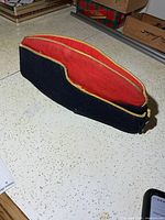 Left side view of WWII RCA officer wedge cap showing navy wool exterior, red crown, gold piping