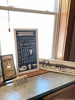 Group shot showing framed bathroom rules print, laundry sign, small block sign, and ceramic face tissue box cover
