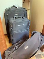 Three pieces of black wheeled luggage grouped