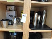 Cabinet shelf with boxed Chef pour-over set, stainless mug, stovetop espresso maker, glass espresso cups, two stainless vacuum bottles on base