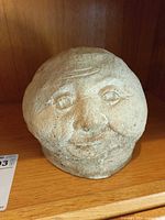 Front three-quarter view of concrete head statue on shelf