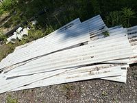 Stack of white corrugated plastic sheets on gravel