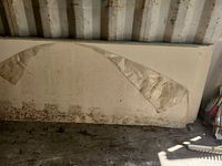 Stacked almond coloured countertop slabs leaning against wall, partial protective film visible