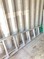 Full view of folded 10-ft aluminum ladder leaning against wall