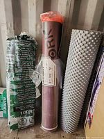Three rolls standing: Eco Quiet underlayment, floating floor pad, dimple waterproof membrane