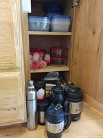 Cabinet showing plastic containers, glass bowls, aluminum pans and insulated drinkware