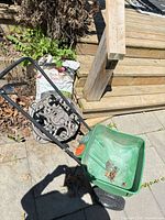 Scotts spreader, Suncast hose reel and bag of black earth on patio