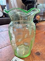 Full view of green depression glass vase showing scalloped rim and floral etching
