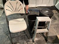 Group shot of folding chair, two trash bins and step ladder