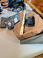 Multiple pairs of folded pants, packaged items, suspenders, EasyOnly belt holster, back scratcher on bed