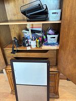 Cabinet shelf with letter trays, bins, and assorted desk supplies