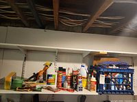 Overall shelf showing chemicals, aerosols, rope coil in crate and painting supplies