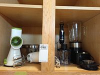Cabinet shelf showing Starfrit slicer, stainless bowls, Sunbeam hand mixer, Master Chef immersion blender parts, Hamilton Beach blender base
