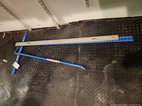 Full view of straight edge, T-square and crow bar on floor