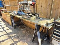 Radial arm saw on bench with folding sawhorses beneath